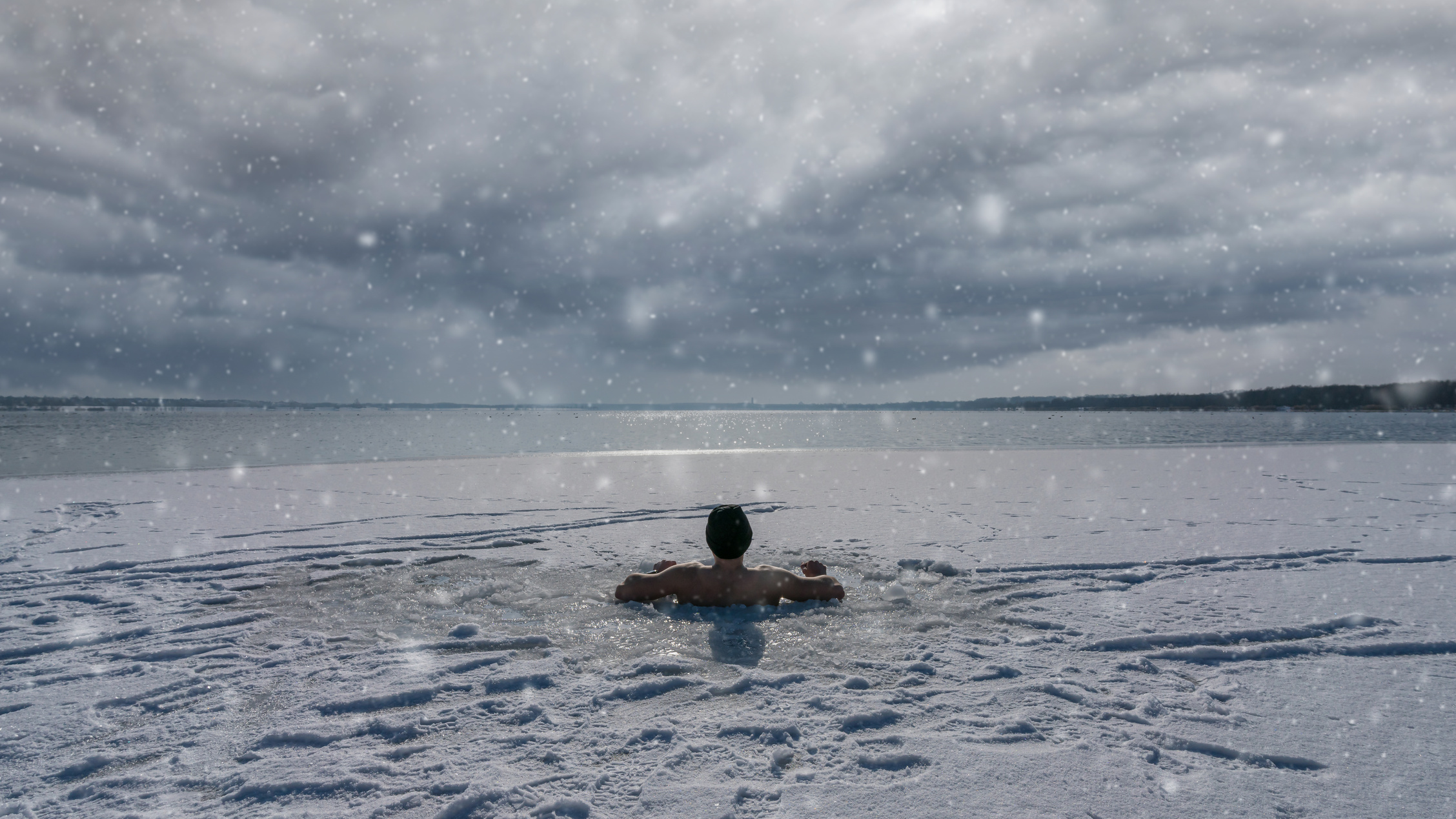 A man sitting an ice hole while having an ice bath